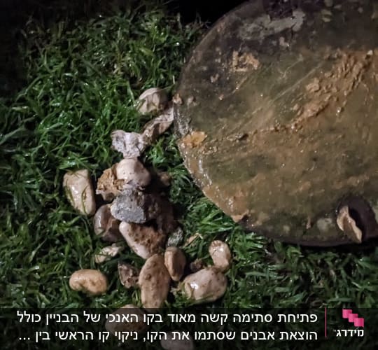 פתח ביוב מכוסה בוץ ואבנים על דשא